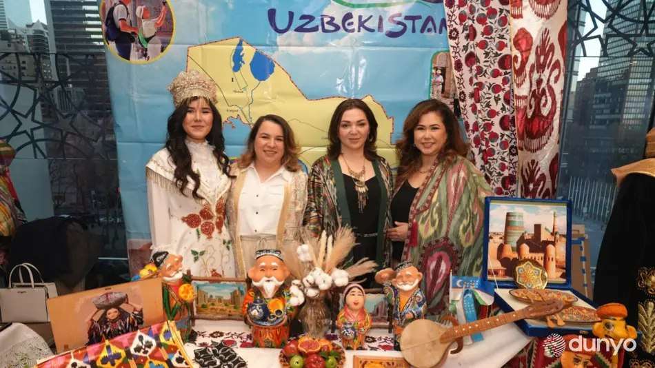Women in traditional dress presenting dolls and crafts at a cultural festival table