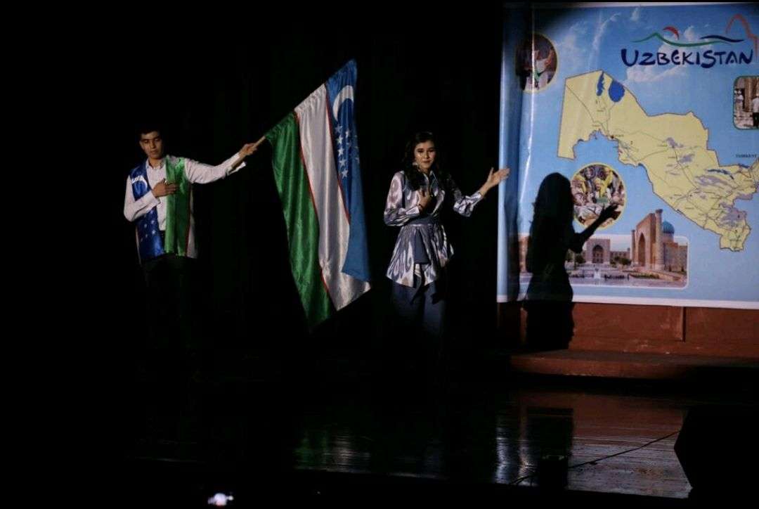 Stage scene with performers before a projected map