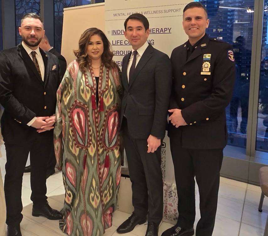Guests in traditional and formal dress with a uniformed officer at an evening event