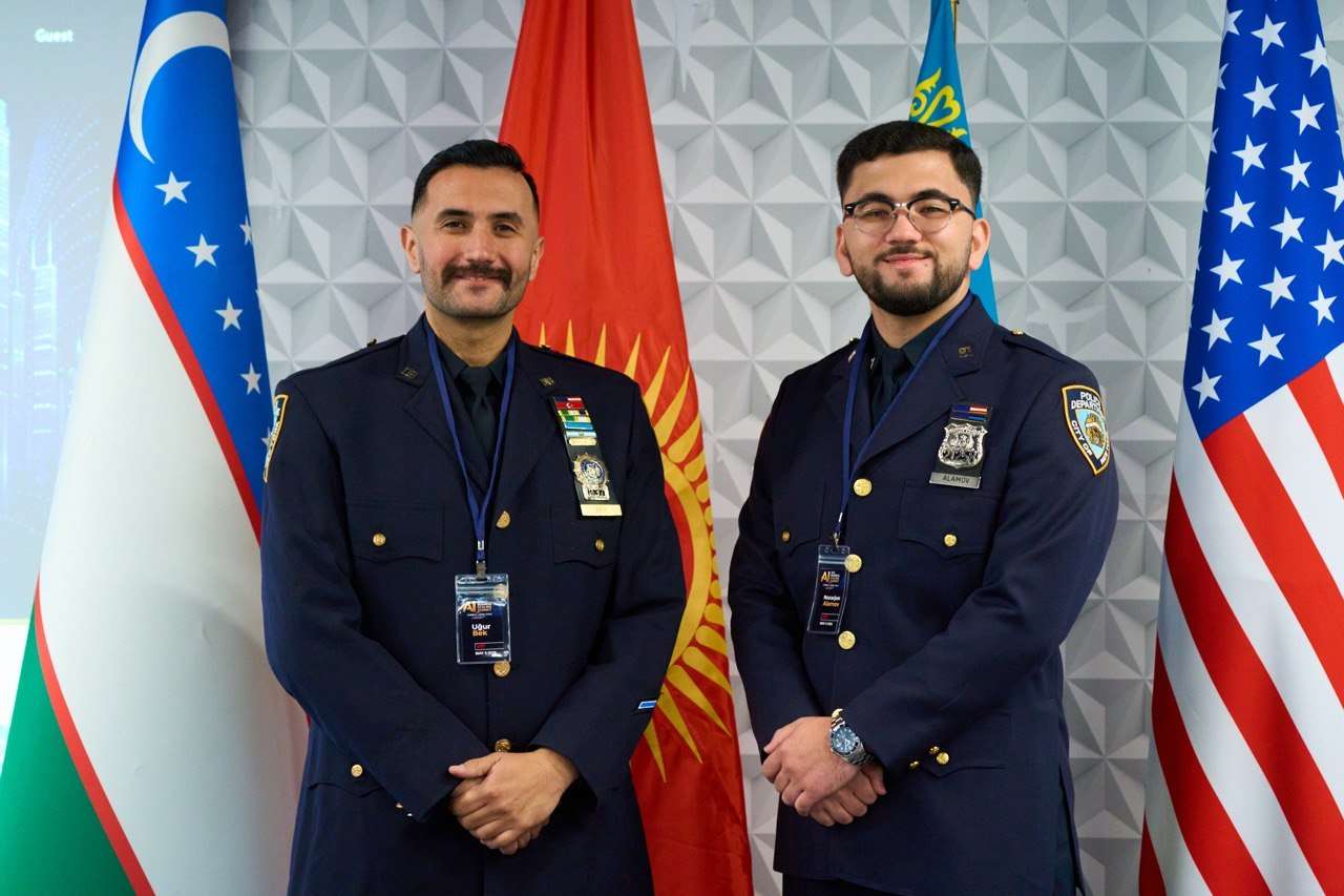 Two uniformed officers before the flags of the United States, Uzbekistan, and Kyrgyzstan