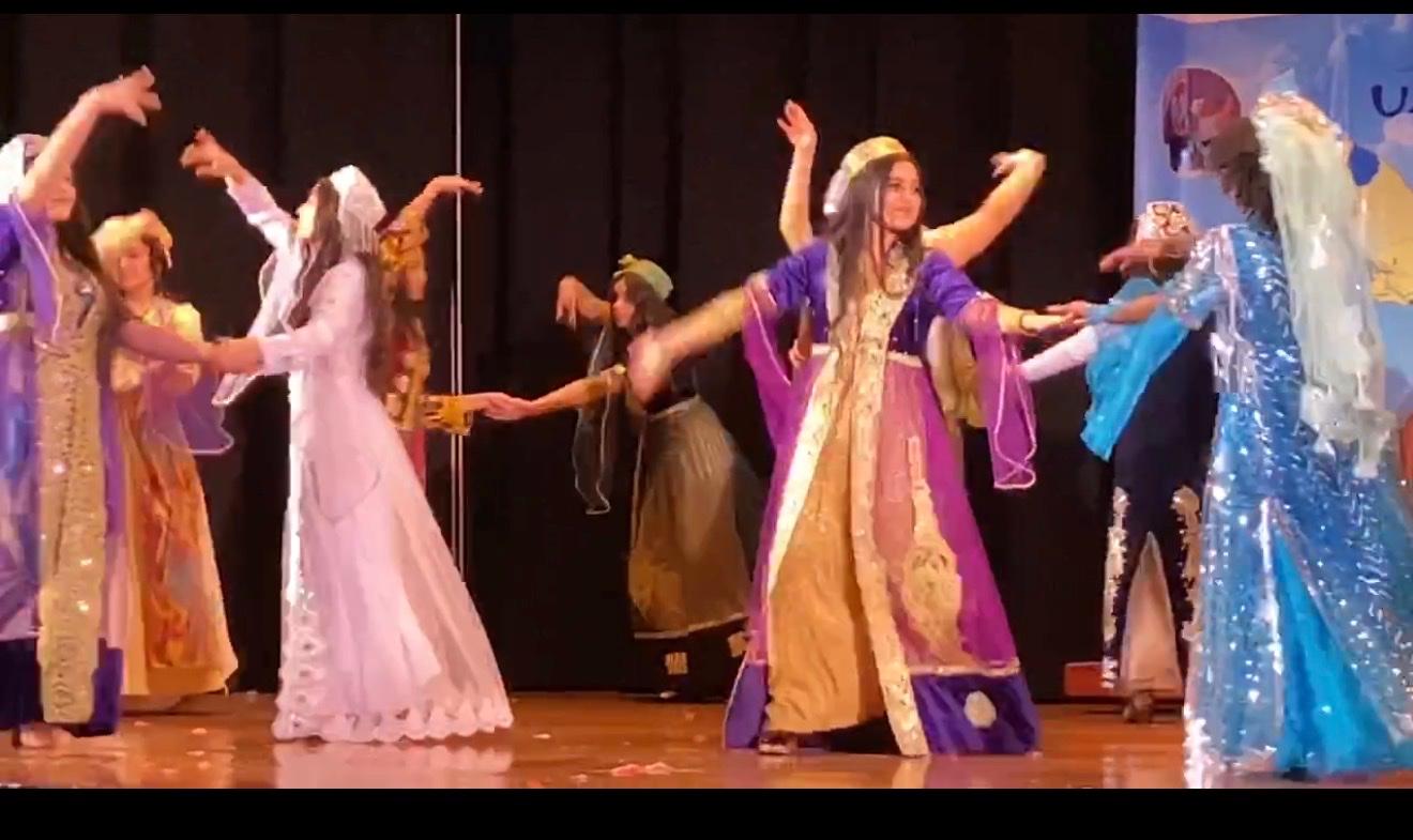 Dancers in flowing traditional gowns performing on a school stage