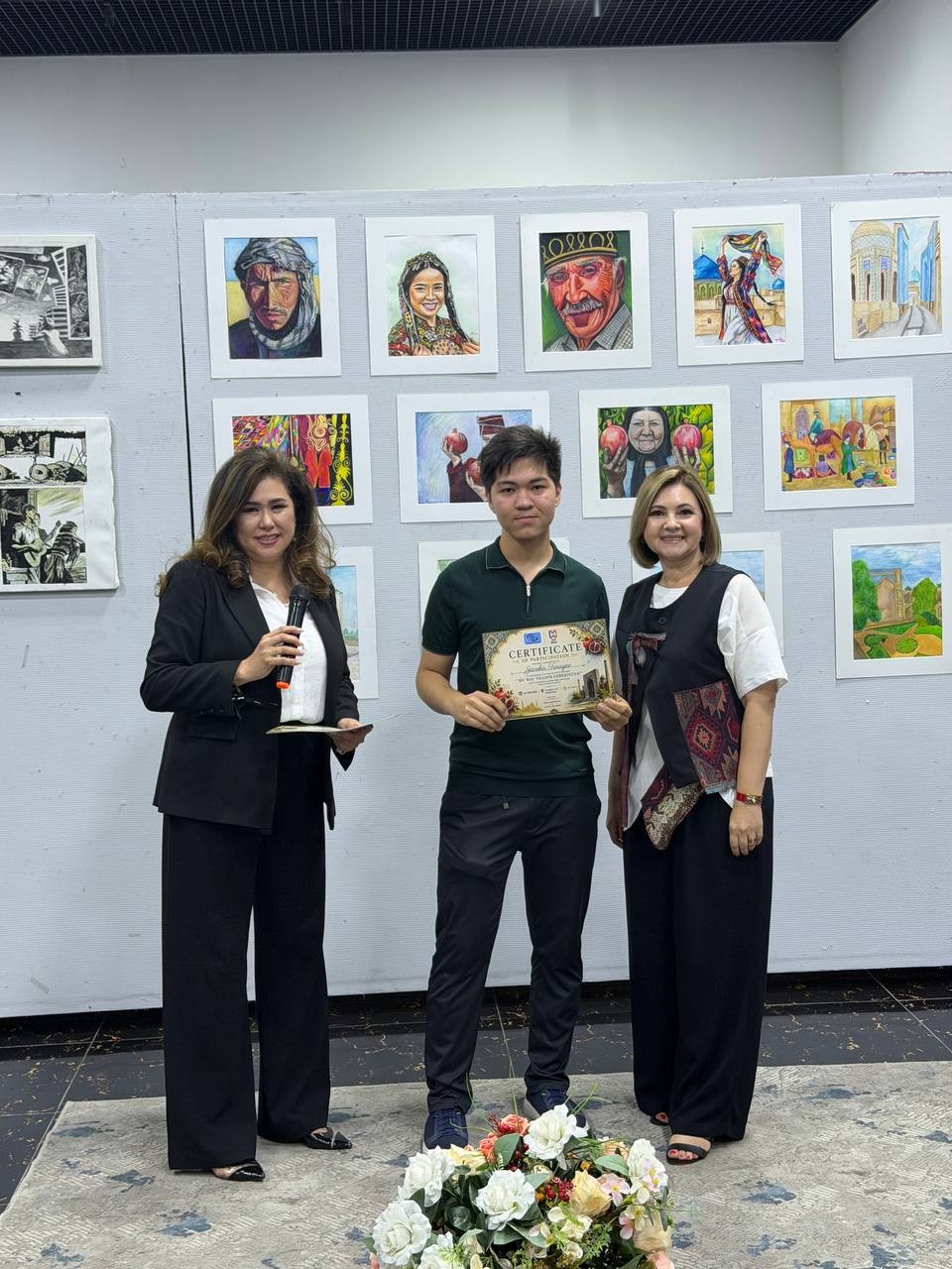 Certificate presented to a young artist at an exhibition, paintings displayed behind